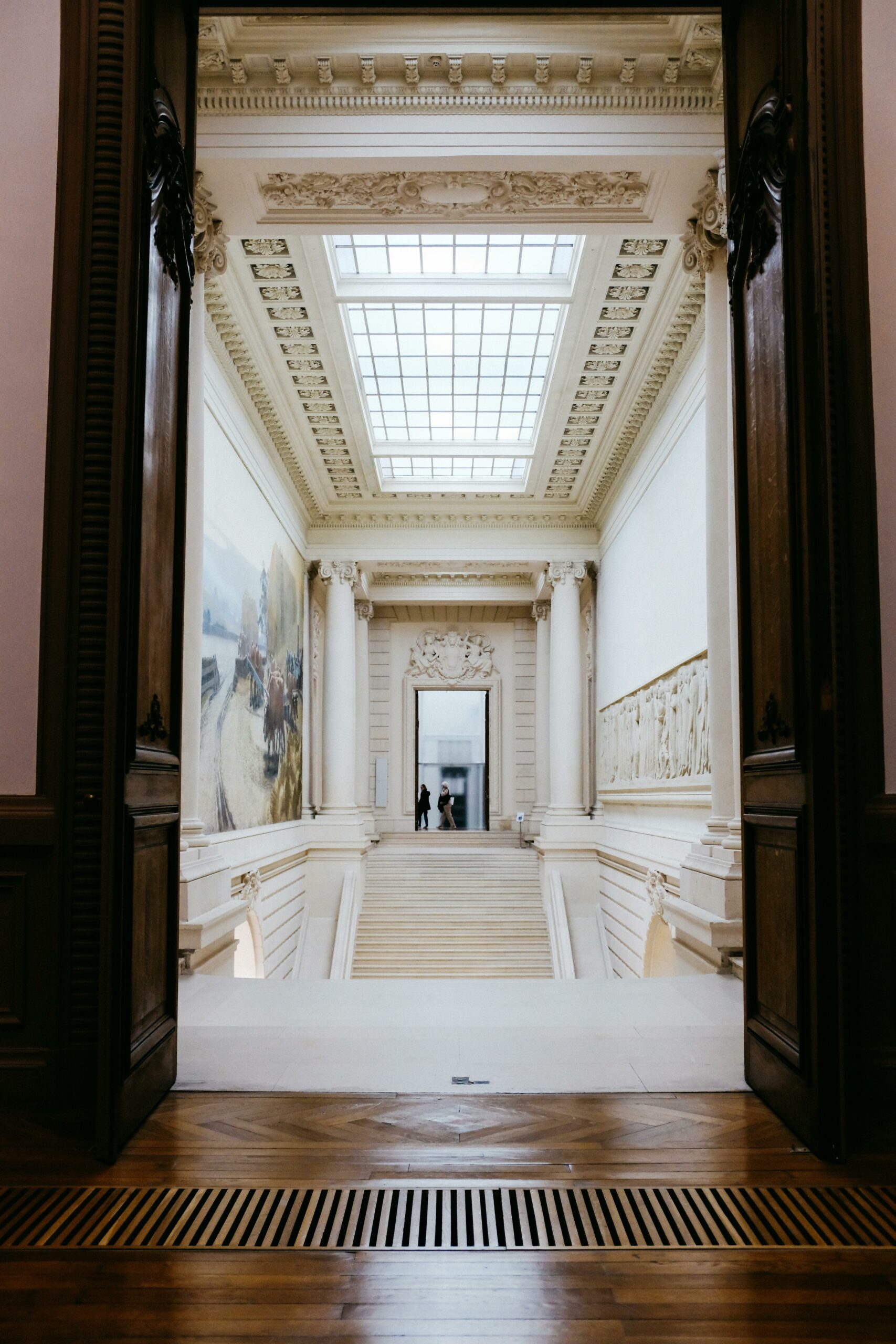 our-services-02 A stunning view through an archway showcasing a grand staircase in a French art museum.